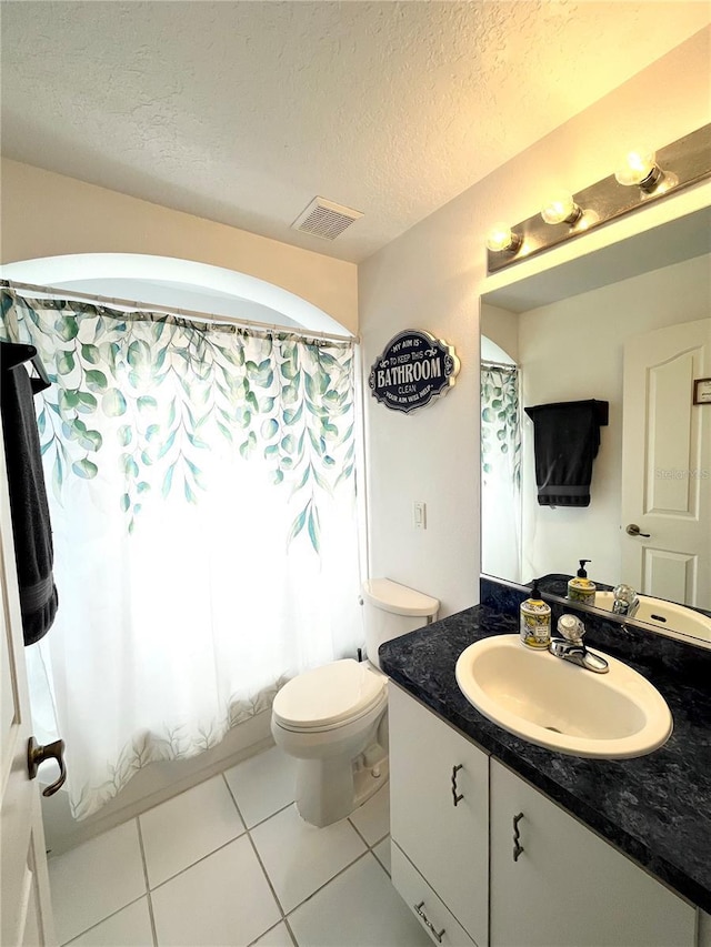 bathroom with vanity, tile patterned flooring, toilet, and a textured ceiling