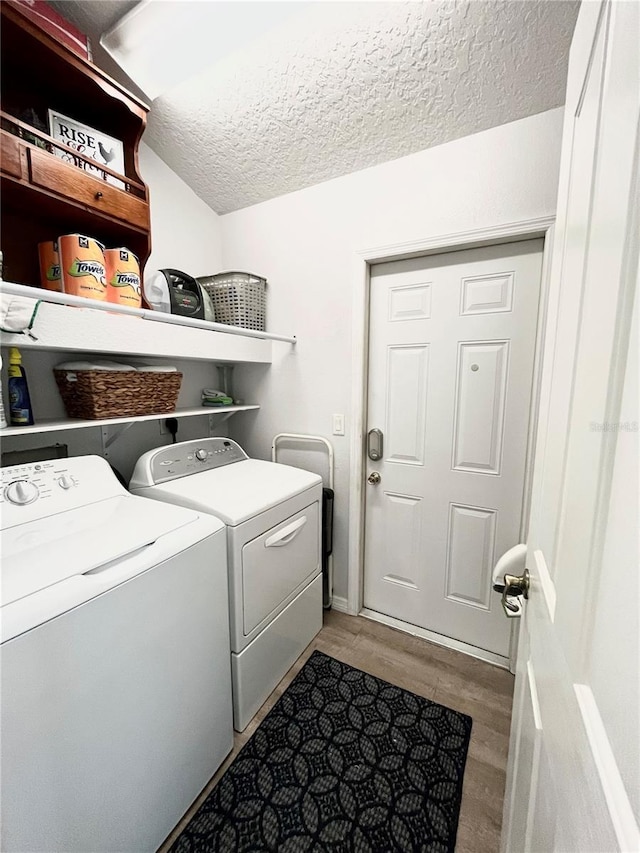 laundry area featuring separate washer and dryer, light hardwood / wood-style floors, and a textured ceiling