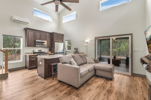 living room featuring sink, a wall mounted AC, ceiling fan, and light hardwood / wood-style flooring