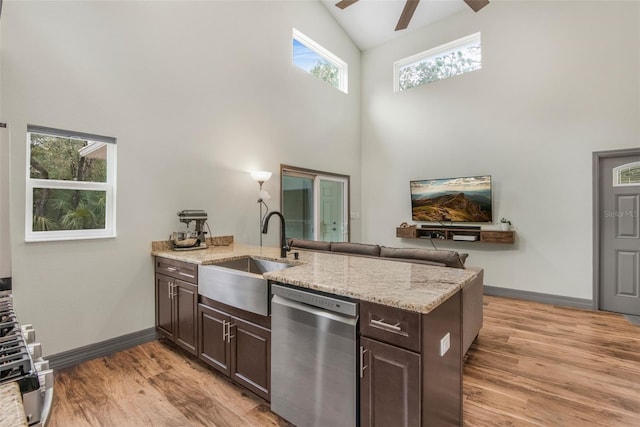 kitchen featuring light stone countertops, dark brown cabinets, sink, and stainless steel dishwasher