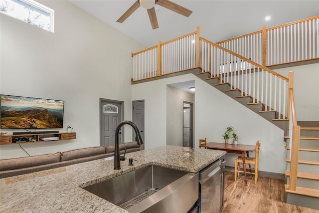 kitchen featuring sink, light hardwood / wood-style flooring, dishwasher, ceiling fan, and high vaulted ceiling