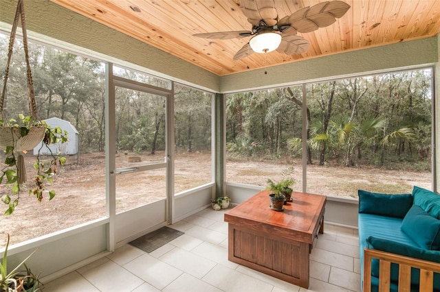 sunroom / solarium featuring a healthy amount of sunlight, wooden ceiling, and ceiling fan