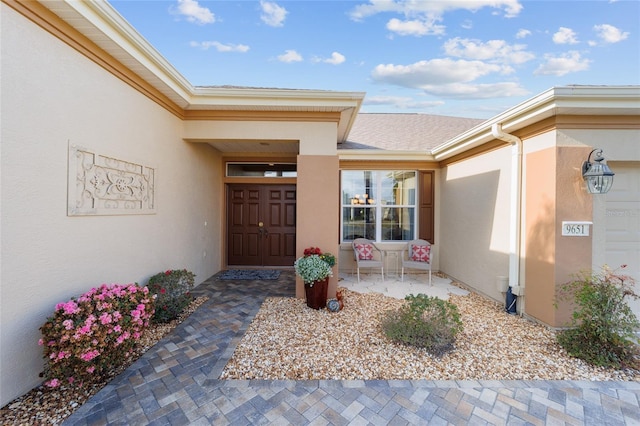 property entrance with an attached garage and stucco siding