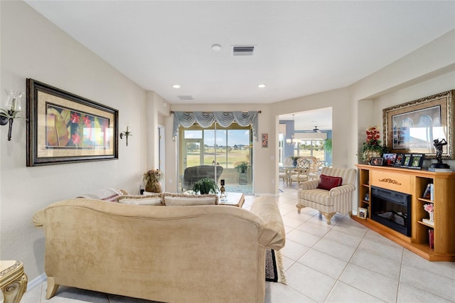 living area featuring light tile patterned floors, recessed lighting, visible vents, a glass covered fireplace, and baseboards