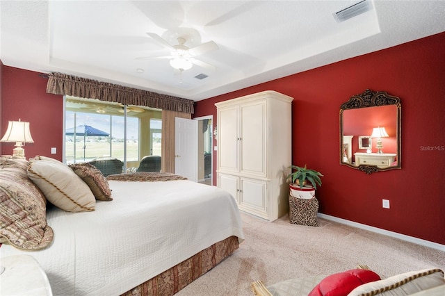 bedroom with visible vents, baseboards, light colored carpet, ceiling fan, and a tray ceiling