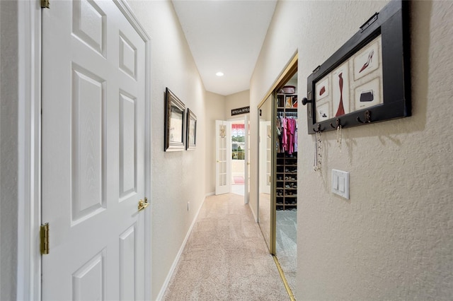 corridor with baseboards, carpet flooring, and a textured wall