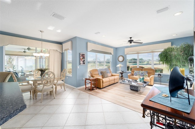 living room with ceiling fan with notable chandelier, light tile patterned flooring, and visible vents