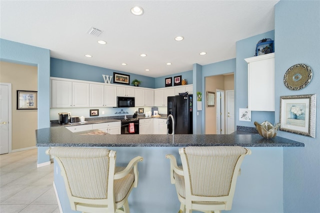 kitchen featuring a peninsula, black appliances, dark countertops, and visible vents