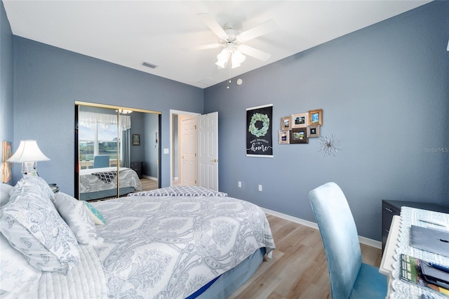 bedroom featuring a closet, visible vents, a ceiling fan, wood finished floors, and baseboards