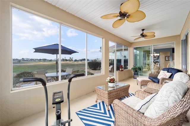 sunroom featuring ceiling fan with notable chandelier