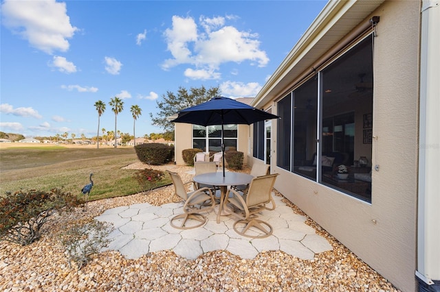 view of patio featuring outdoor dining space and a sunroom