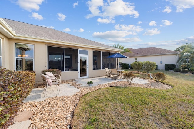 back of house with a patio, a shingled roof, a sunroom, a lawn, and stucco siding