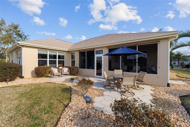 rear view of house featuring a yard, a sunroom, a patio area, and stucco siding