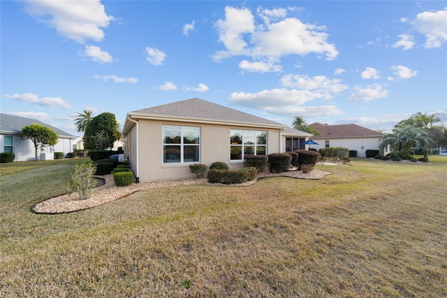 back of property with stucco siding and a yard