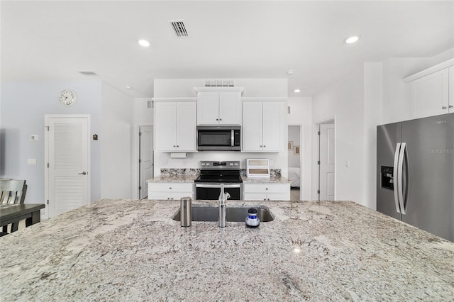 kitchen with appliances with stainless steel finishes, white cabinets, and light stone counters