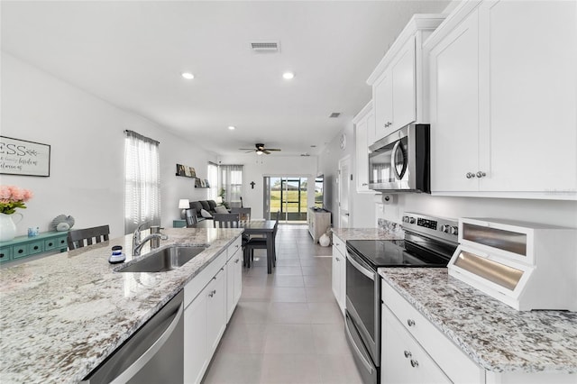 kitchen featuring sink, white cabinetry, light stone counters, light tile patterned floors, and stainless steel appliances