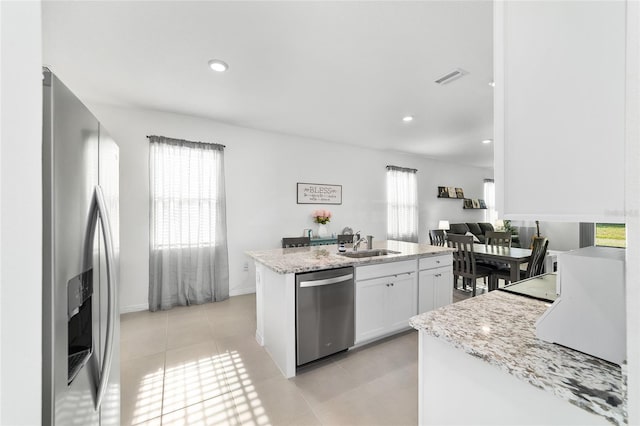 kitchen featuring light tile patterned flooring, white cabinetry, sink, light stone counters, and stainless steel appliances