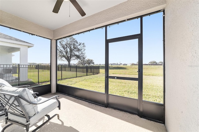 sunroom with a wealth of natural light, a rural view, and ceiling fan