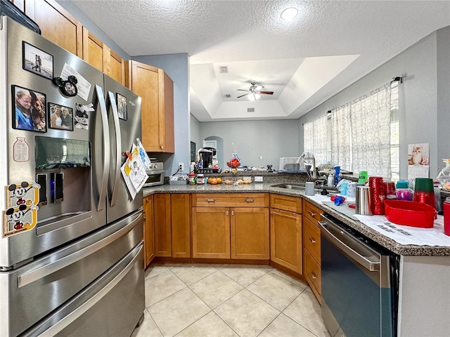 kitchen featuring appliances with stainless steel finishes, sink, light tile patterned floors, and kitchen peninsula