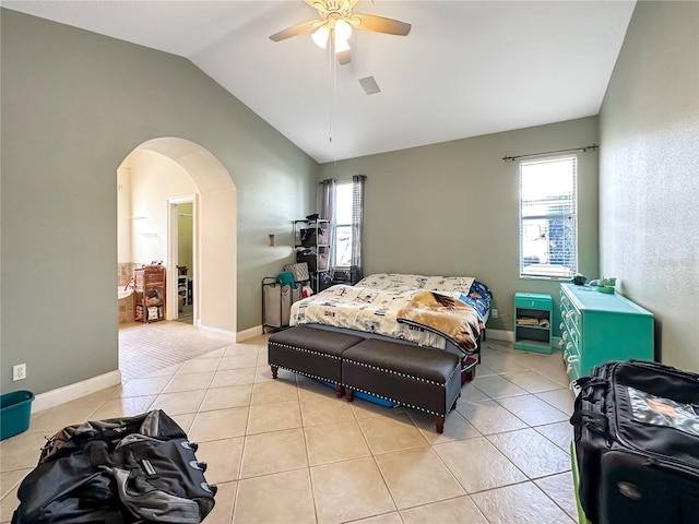 tiled bedroom featuring ceiling fan, vaulted ceiling, and multiple windows