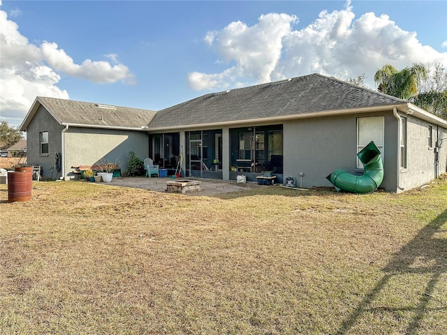 rear view of house with a patio area, a fire pit, and a lawn