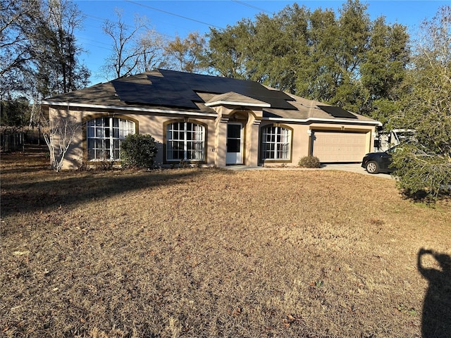 ranch-style house featuring a garage, a front lawn, and solar panels