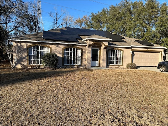 ranch-style home with a garage, a front yard, and solar panels