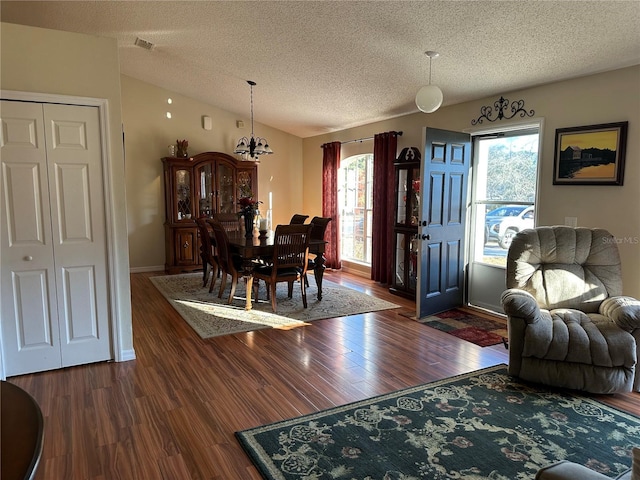 dining room with vaulted ceiling, dark hardwood / wood-style floors, and a textured ceiling