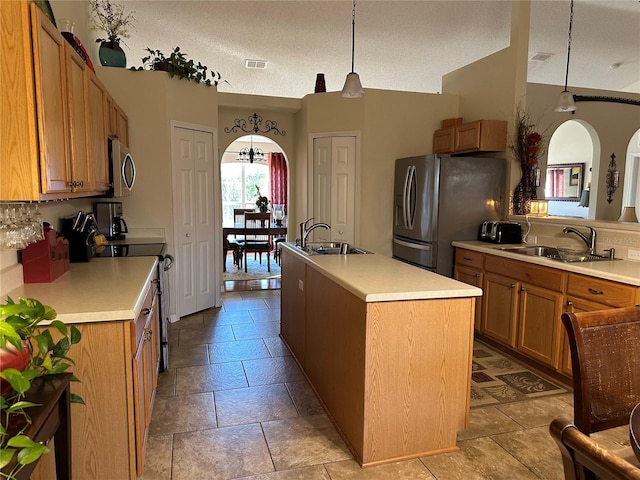 kitchen with sink, decorative light fixtures, stainless steel appliances, and a center island with sink