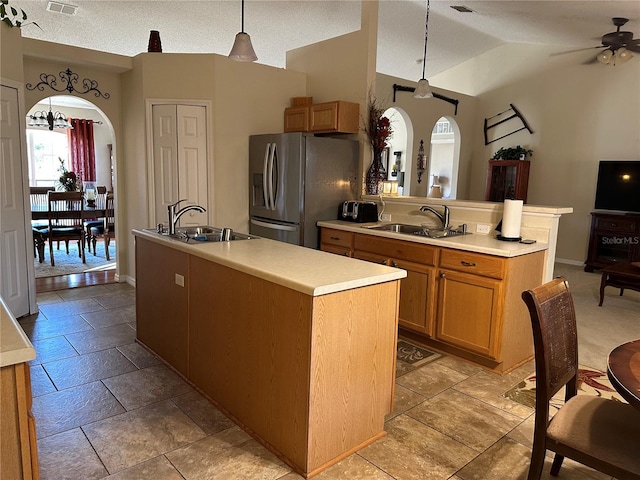 kitchen with sink, hanging light fixtures, ceiling fan, stainless steel refrigerator with ice dispenser, and a center island with sink