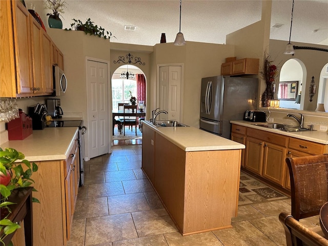 kitchen featuring pendant lighting, sink, stainless steel appliances, and a center island with sink