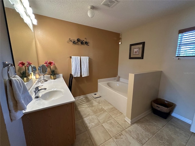 bathroom featuring vanity, a tub to relax in, tile patterned flooring, and a textured ceiling