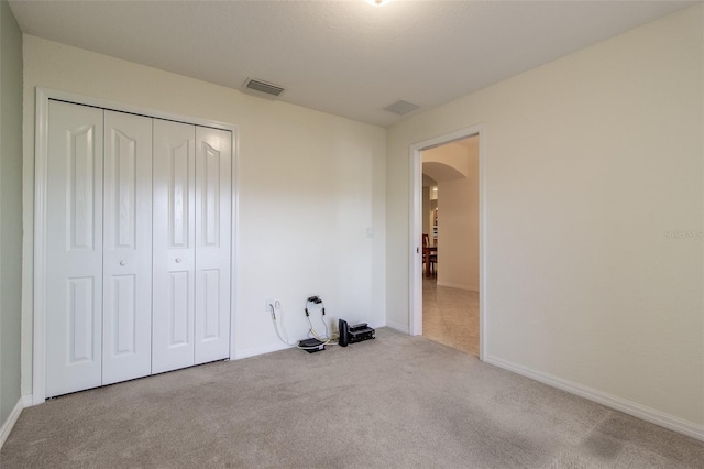 unfurnished bedroom with a closet and light carpet