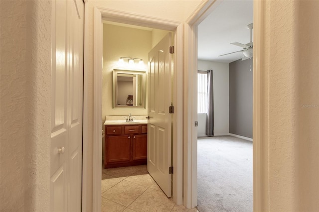 corridor featuring sink and light carpet