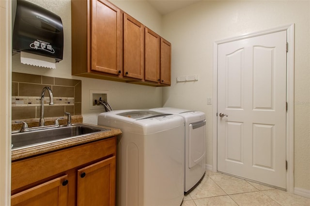 laundry room featuring light tile patterned flooring, cabinets, sink, and washing machine and clothes dryer