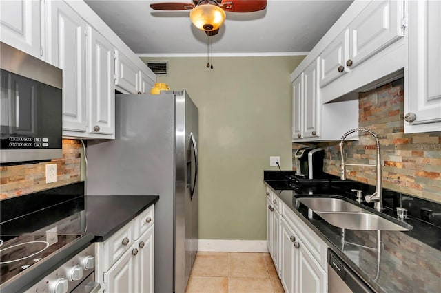 kitchen featuring sink, white cabinetry, light tile patterned floors, appliances with stainless steel finishes, and backsplash