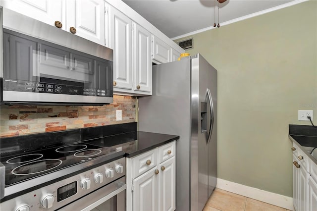 kitchen featuring tasteful backsplash, white cabinetry, light tile patterned floors, stainless steel appliances, and crown molding