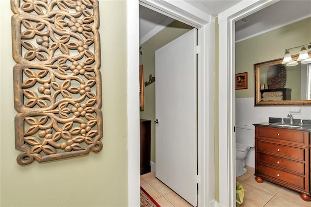 bathroom featuring tile patterned flooring, vanity, crown molding, and toilet