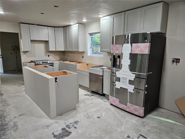 kitchen with a textured ceiling, white cabinets, and appliances with stainless steel finishes