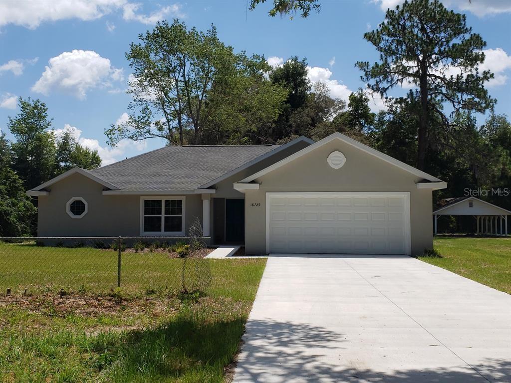 single story home with stucco siding, concrete driveway, a front yard, fence, and a garage