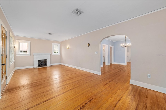 unfurnished living room with ornamental molding, a brick fireplace, and light wood-type flooring