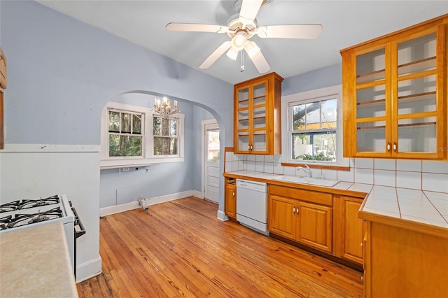 kitchen featuring sink, tile countertops, light wood-type flooring, dishwasher, and backsplash