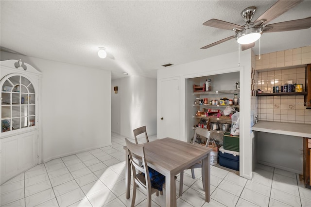 dining area with ceiling fan, a textured ceiling, and light tile patterned floors