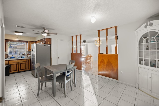 tiled dining space with ceiling fan, sink, and a textured ceiling