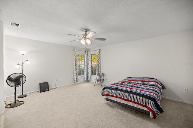 carpeted bedroom with ceiling fan and a textured ceiling