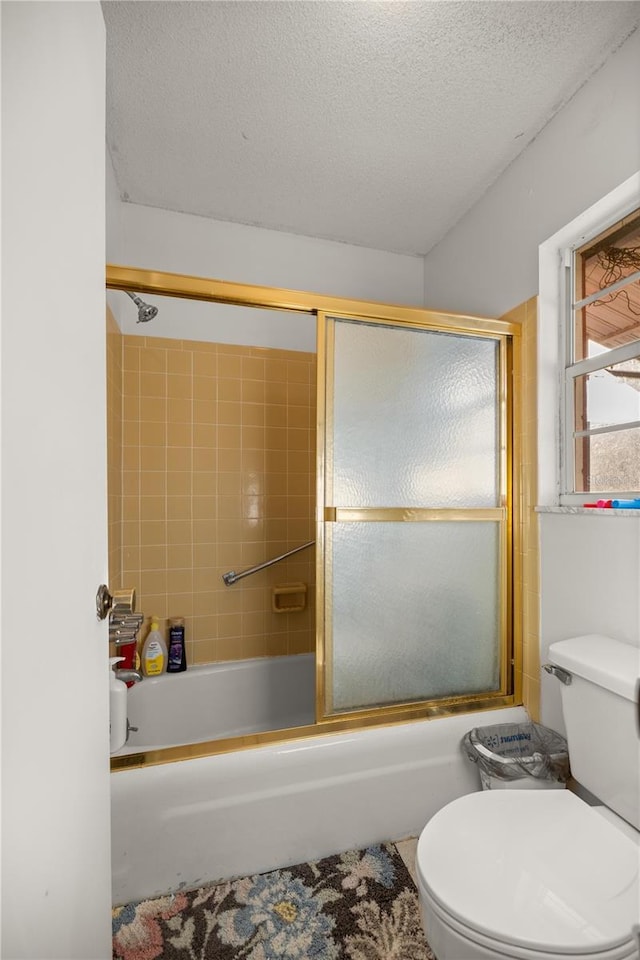 bathroom with toilet, bath / shower combo with glass door, and a textured ceiling