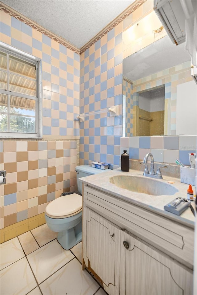 bathroom featuring toilet, tile walls, a textured ceiling, vanity, and tile patterned flooring