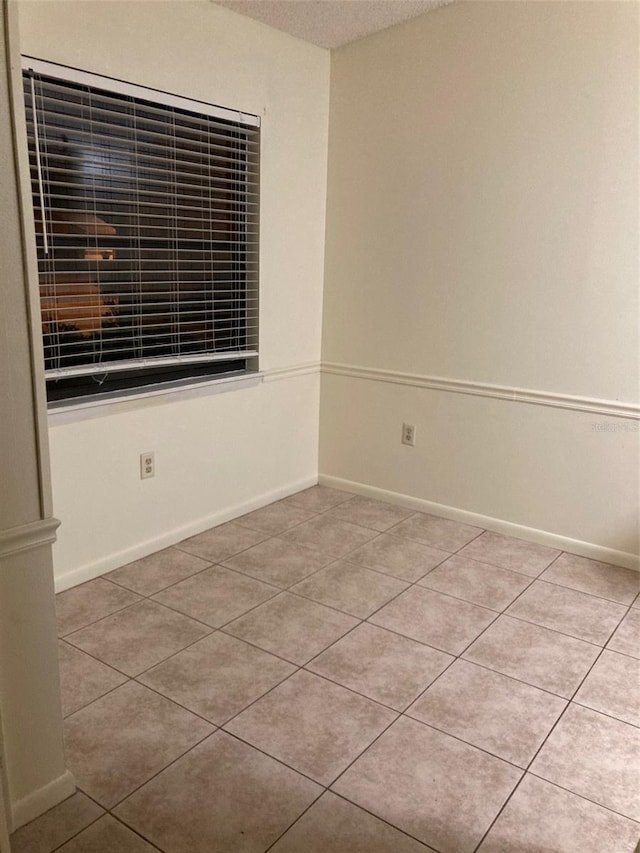 unfurnished room with a textured ceiling and light tile patterned floors