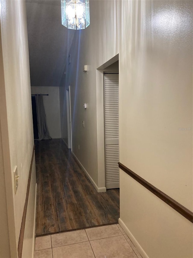 hall featuring lofted ceiling, a chandelier, and tile patterned flooring