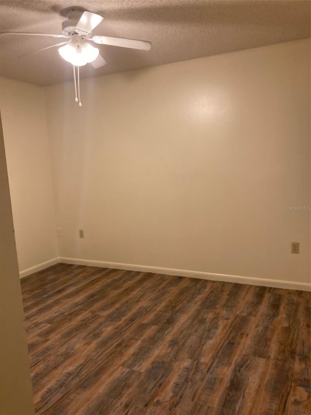 empty room with dark wood-type flooring, ceiling fan, and a textured ceiling